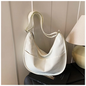 Detail of white half-moon canvas bag featuring unique curved stitching and adjustable strap