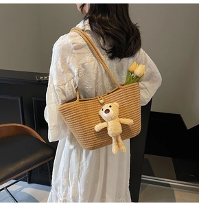 Detail of khaki woven tote bag featuring a pearl clasp and cute plush bear charm