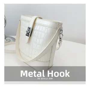 Detail einer weißen Bucket Bag mit Krokodilmuster, Silberbeschlägen und Logo