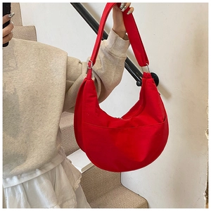 Detail of red canvas crossbody crescent bag showing side pocket and adjustable strap