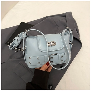 Gros plan du mini sac seau bleu clair avec fermoir rotatif et détail de ceinture à œillets