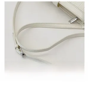 Detail der weißen Beuteltasche mit Krokodilprägung, verstellbarem Riemen und Reißverschluss