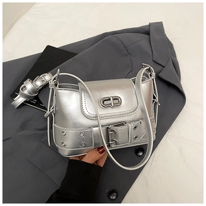 Détail du sac seau argenté miroir avec boucle CD métallique sur fond de costume gris