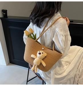 Detail of straw woven tote bag with white pearl button and cute cream teddy bear charm