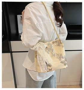 Detail of cream shoulder bag featuring silver butterfly embroidery and lace pearl bow