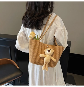 Detail of straw woven tote bag with plush bear charm and white floral tulip decoration
