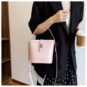 Détail du sac seau rose à motif crocodile avec fermoir argenté et poignée supérieure
