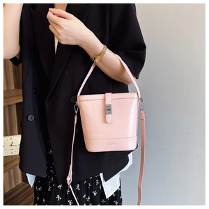 Detail der rosa Bucket Bag mit Krokodilprägung, silbernem Drehverschluss und Riemen