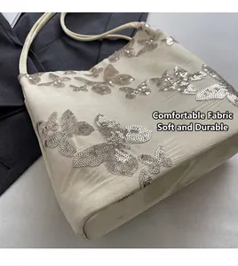 Detailed view of white silk fabric with silver sequin butterfly embroidery on tote bag