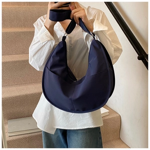 Detail of dark blue crescent canvas bag with adjustable strap and silver metal buckle