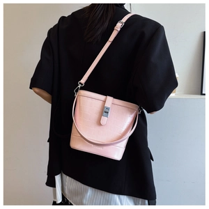 Pink bucket bag with crocodile pattern and silver twist lock shown on model's shoulder