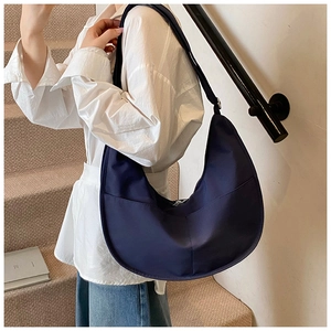 Detail of navy blue large nylon crescent bag showing its size and matte texture on model