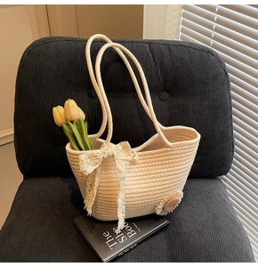 Close-up of beige woven tote bag with lace bow sunflower charm and pearl detail