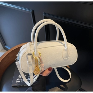 Detail of white lychee leather barrel bag with tennis racket charm on black background