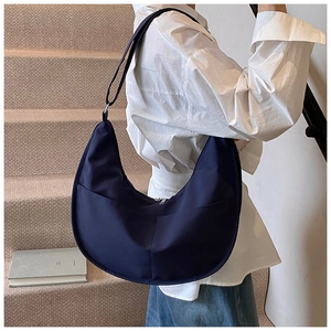 Detail of navy blue hobo bag with adjustable strap and front pocket on a model