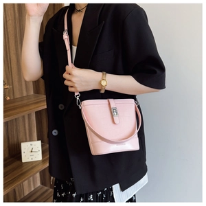 Close-up of pink crocodile pattern bucket bag showing metal lock and shoulder strap details