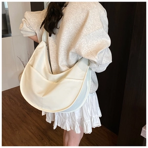 Detail view of large off-white canvas hobo bag with wide shoulder strap and side pockets