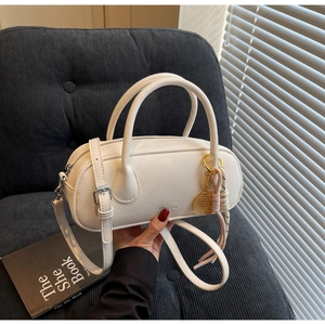 Detail of white lychee leather boston bag with golden tennis racket pendant and charms