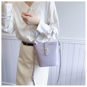 Détail du sac seau lavande effet croco avec boucle métallique sur une tenue élégante