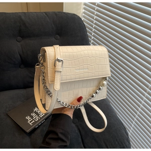 Detail of cream crocodile pattern bag with decorative pearl and silver chain handle