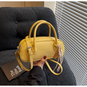 Detail of yellow lychee texture boston bag with dual handles and woven pendant charm