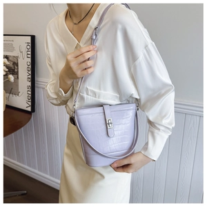Close-up of lavender croc-effect bucket bag with silver turn-lock clasp on a model