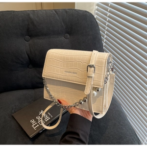 Close-up of cream crossbody bag featuring crocodile texture and pearl chain details
