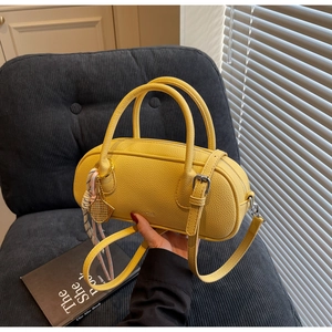 Detail of yellow lychee texture boston bag with tennis racket charm on blue chair