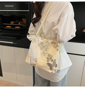 Detail of sequin butterfly embroidery and lace bow on chic cream shoulder tote bag