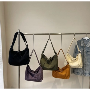 Row of colorful canvas crossbody bags with drawstring bow details and front pocket