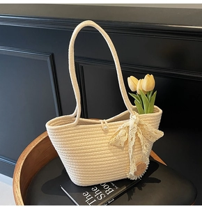 Detail of woven straw tote bag with pearl button closure and decorative lace bow