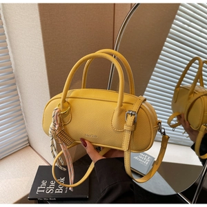 Detail view of bright yellow litchi pattern leather handbag with tennis racket charm