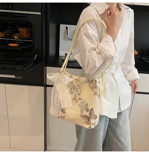 Detail of cream tote bag with sequined butterfly pattern and lace pearl bow charm