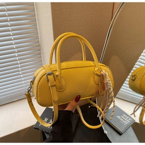 Detail of yellow lychee texture leather handbag with tennis racket charm and woven strap