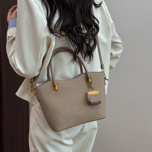 Detail of woven texture tote bag with gold chain charm and mini pouch in beige