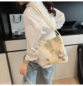 Close-up of cream shoulder bag featuring silver butterfly sequins and lace bow charm