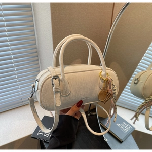 Macro shot of white lychee-patterned leather cylinder bag with gold tennis racket charm