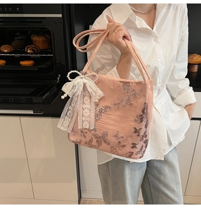 Detailed close-up of pink satin tote bag featuring sequin butterflies and lace pearl bow