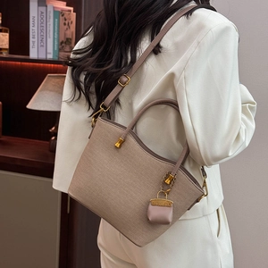 Detailed view of woven tote bag with adjustable strap and mini coin purse charm