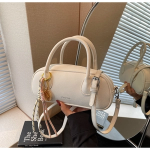 Detailed close-up of a white lychee grain leather handbag with tennis racket charm