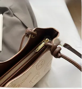 Close-up of golden metal zipper and bear embossed texture on beige bucket bag