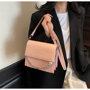 Detailed close-up of pink croc-textured bag with pearl chain and fashion lettering