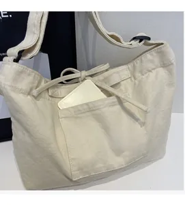 Detail of canvas tote bag showing outer pocket space and adjustable shoulder strap