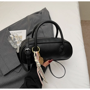 Close-up of black lychee grain leather Boston bag with a tennis racket charm and silver logo