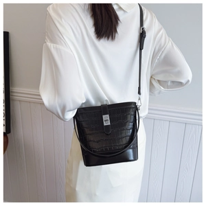 Detail of black crocodile texture bucket bag with silver lock and adjustable strap