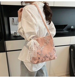 Detail of pink tote bag with sequin butterflies, lace bow and pearl pendant on shoulder strap