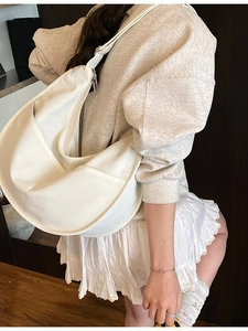 Minimalist white large canvas hobo bag worn by model in a modern interior setting