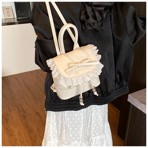 Detalle de mini mochila blanco crema con encaje delicado y un lazo decorativo dulce