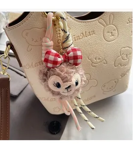 Cute pink plush pendant with checkered bow hanging on a textured bucket bag