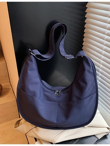 Minimalist purple nylon hobo bag with adjustable strap and front pocket on creative display